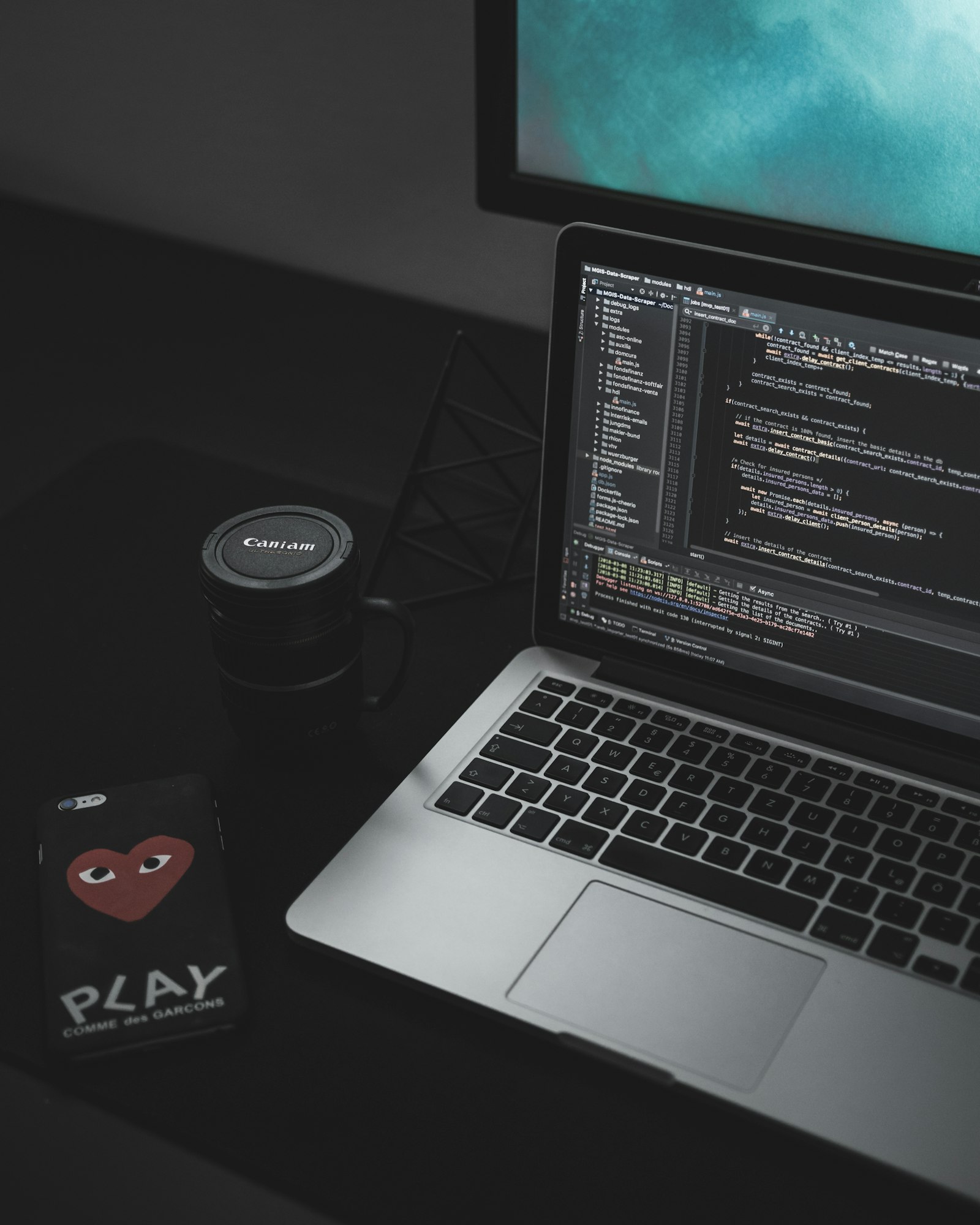 A laptop with code on screen in a dark, focused workspace